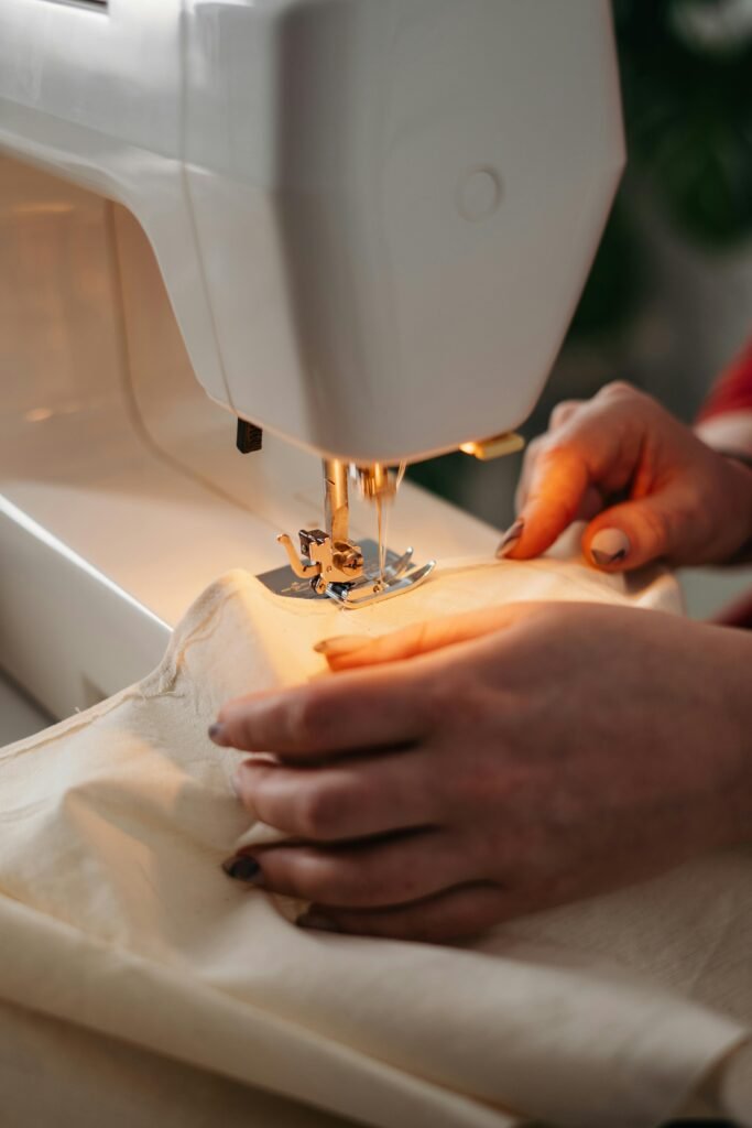 pexels-photo-3738095-3738095 Detailed view of sewing process with hands guiding fabric on a machine.
